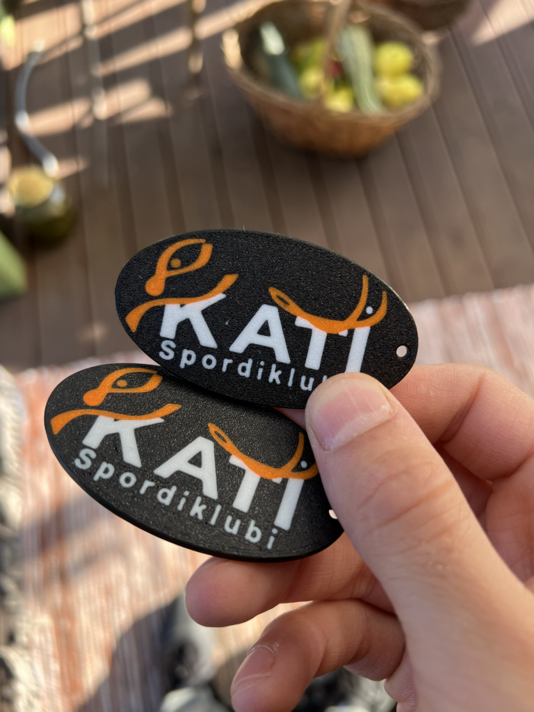 Kaks Kati spordiklubi logoga 3D-prinditud võtmehoidjat mitmevärvilise printimisega.